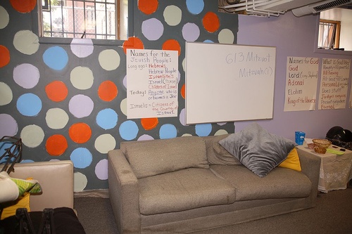 a room with a couch, chair and bulletin board on the wall