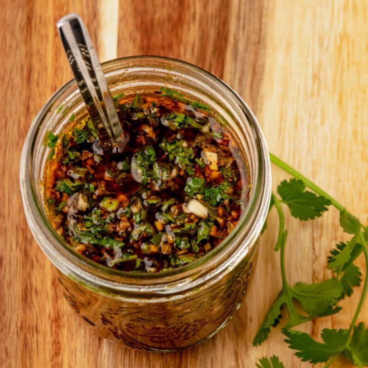 a glass jar filled with food sitting on top of a wooden table next to a green leafy plant