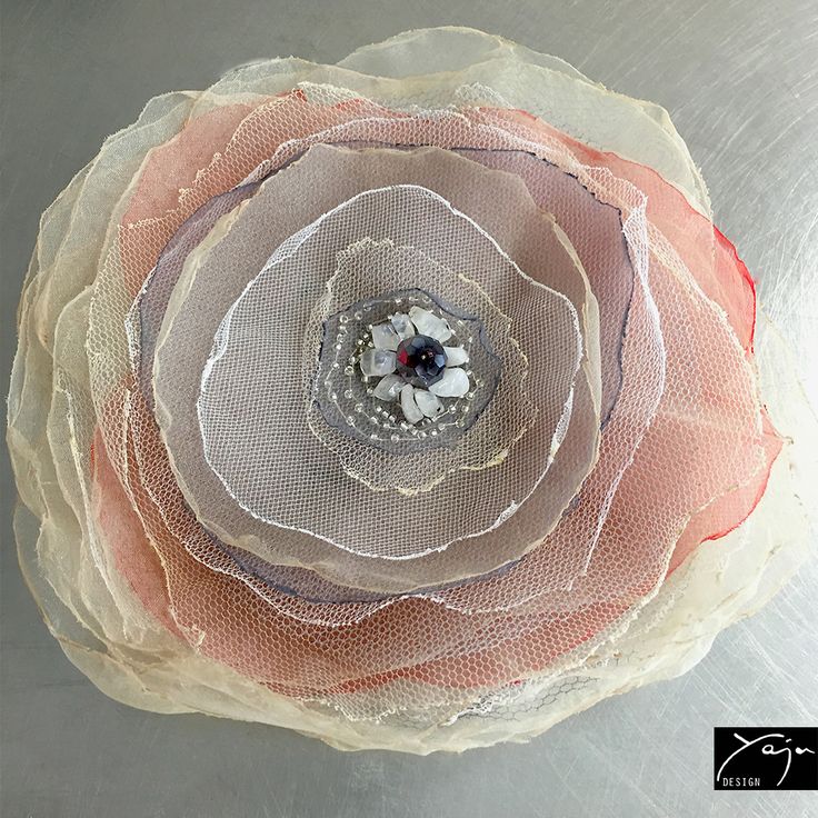 a close up of a flower on a metal surface with mesh netting around the center