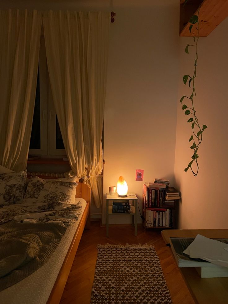 a bed sitting next to a lamp on top of a wooden table in a bedroom