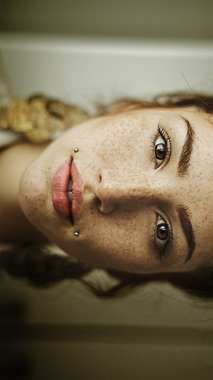 a woman with freckles and piercings on her face