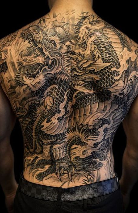 the back of a man with tattoos on his body and dragon tattoo on his chest