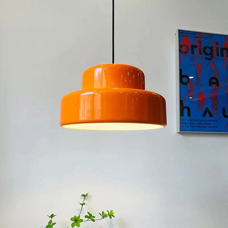 an orange lamp hanging from the ceiling next to a potted plant