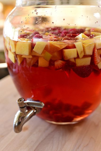 a pitcher filled with fruit and water on top of a wooden table