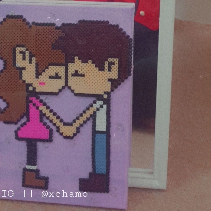 a cross - stitch picture of two people holding hands, with the frame in front of them