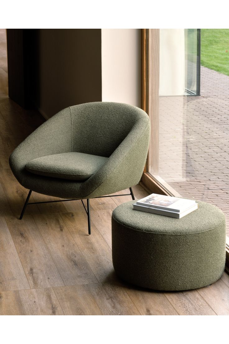 a green chair and ottoman in front of a sliding glass door with a book on it