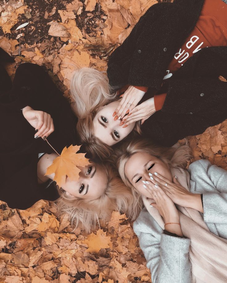 three women laying on the ground with leaves around them