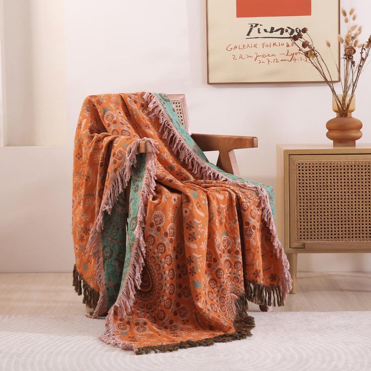 an orange blanket sitting on top of a wooden chair