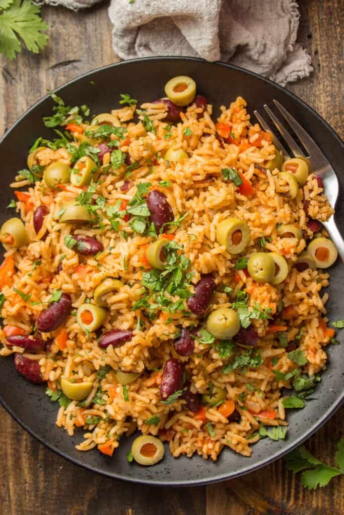 rice salad with olives and parsley in a black bowl