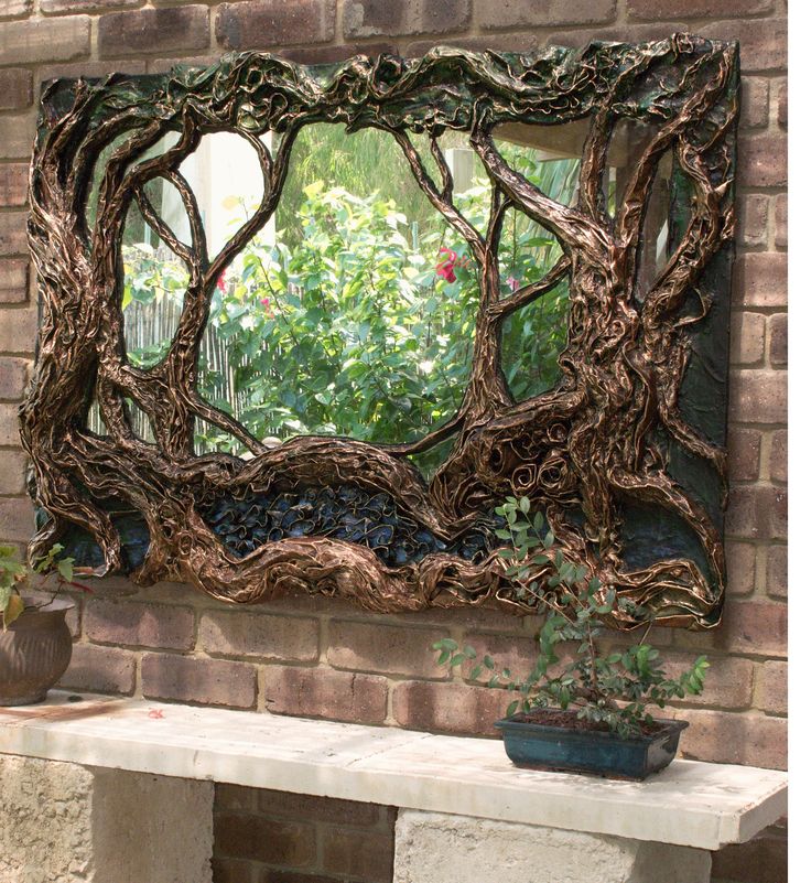 a mirror sitting on top of a brick wall next to a potted plant in front of it