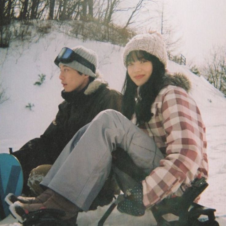 two people sitting on the ground with snowboards