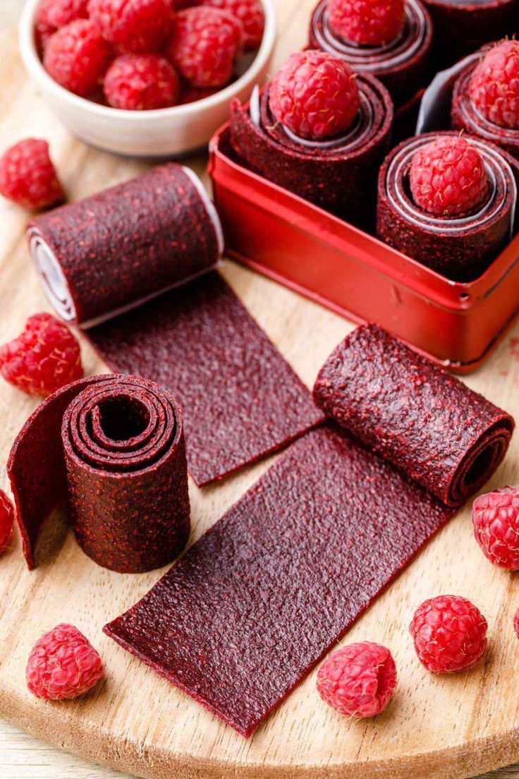 raspberry rolls on a cutting board next to a bowl of raspberries