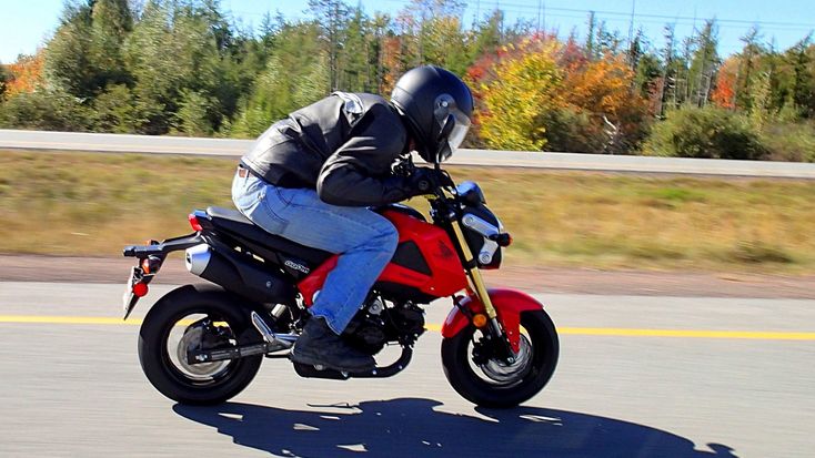 a man riding on the back of a red motorcycle