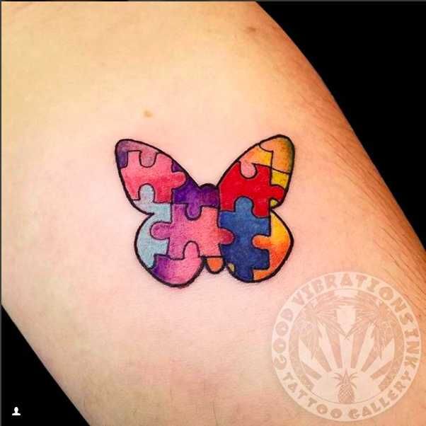 a colorful butterfly made out of puzzle pieces on the thigh, with one piece missing