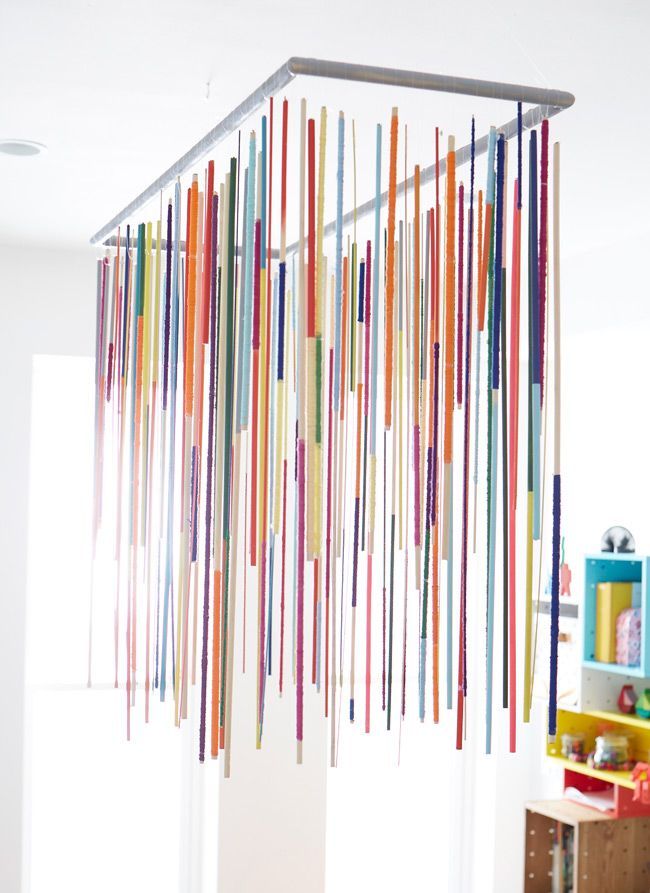 a room filled with lots of different colored sticks hanging from the ceiling over a table