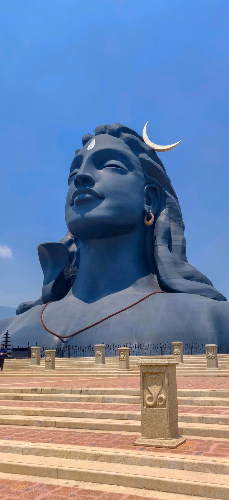 the large statue is blue and has a crescent on it's head, with stairs leading up to it