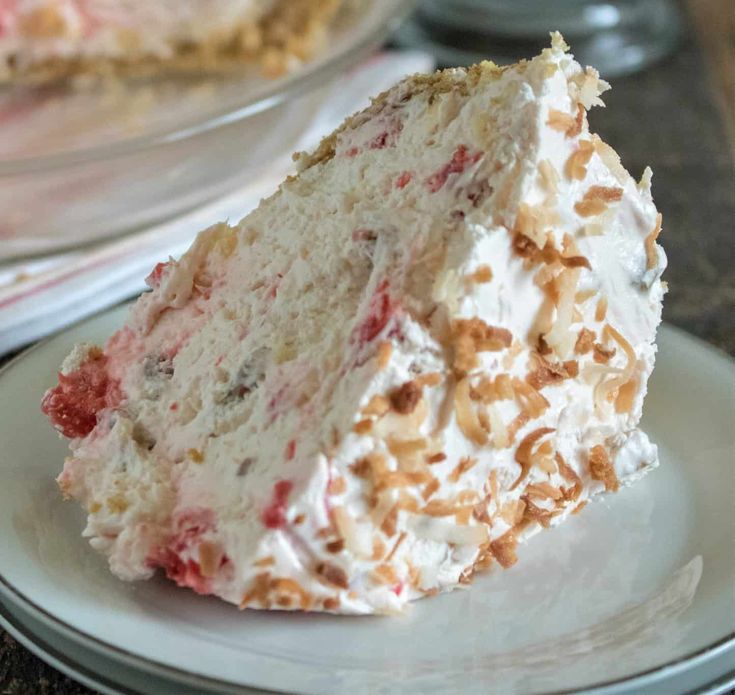 a piece of cake with white frosting and strawberries on it sitting on a plate