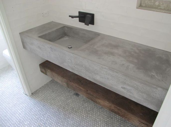 a concrete sink sitting on top of a wooden bench next to a wall mounted faucet