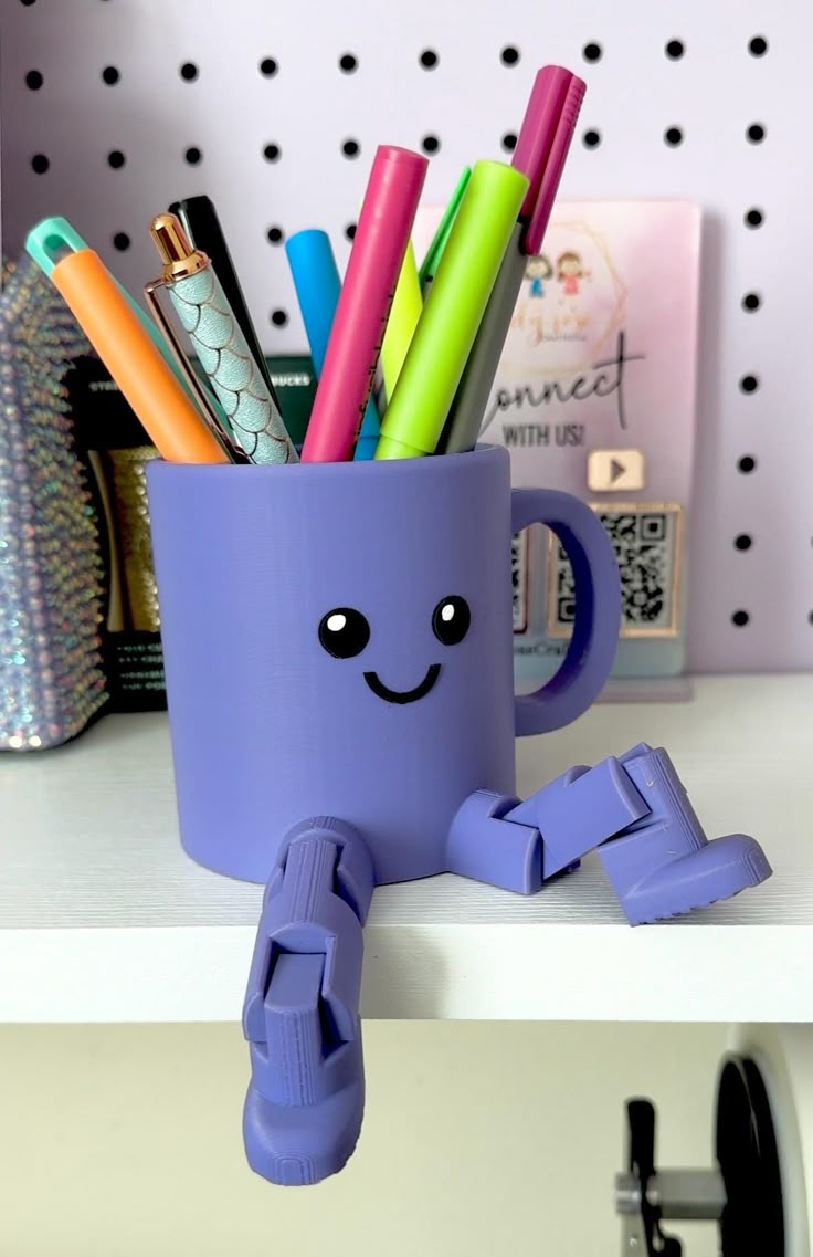 a purple cup filled with markers and pens sitting on top of a white counter next to a shelf