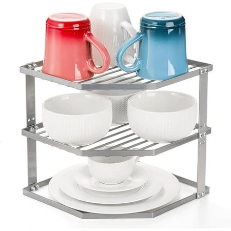 three cups and two saucers are stacked on a metal rack, with plates underneath