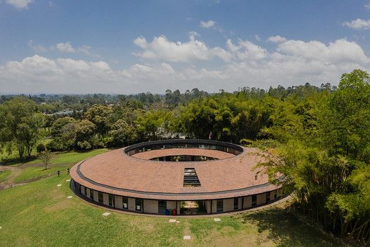 an aerial view of a circular building in the middle of a field with trees around it