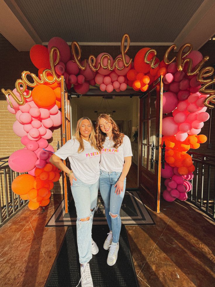 two women standing in front of an entrance decorated with balloons and the words road to life