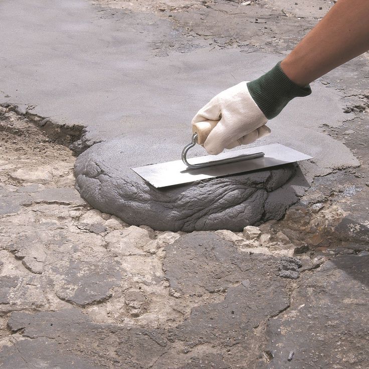 a person is using a knife to cut into a piece of cement on the ground