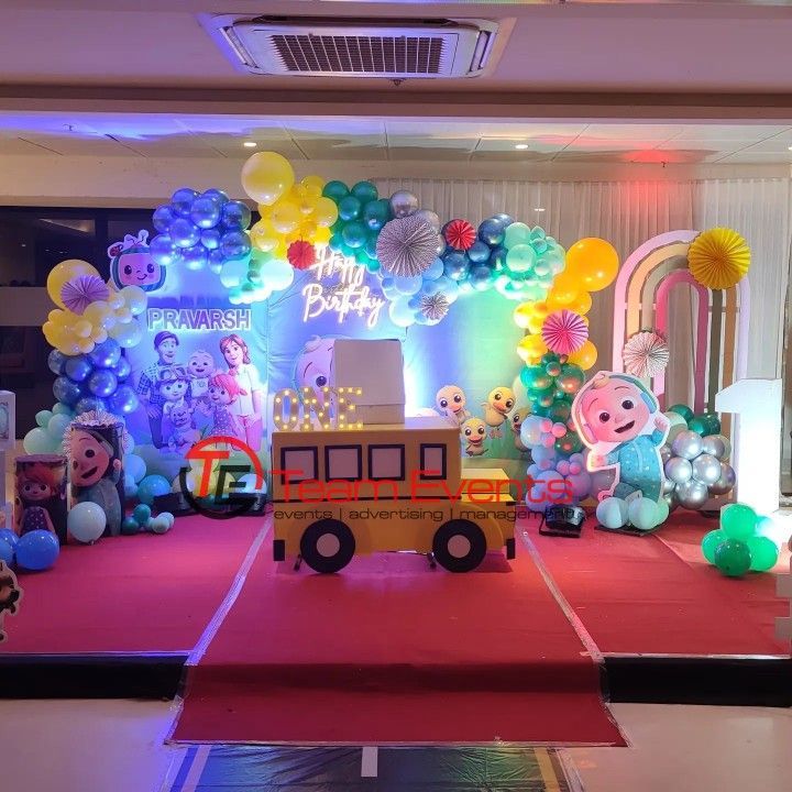 a birthday party with balloons and decorations on the floor, including a fire truck in front of an arch