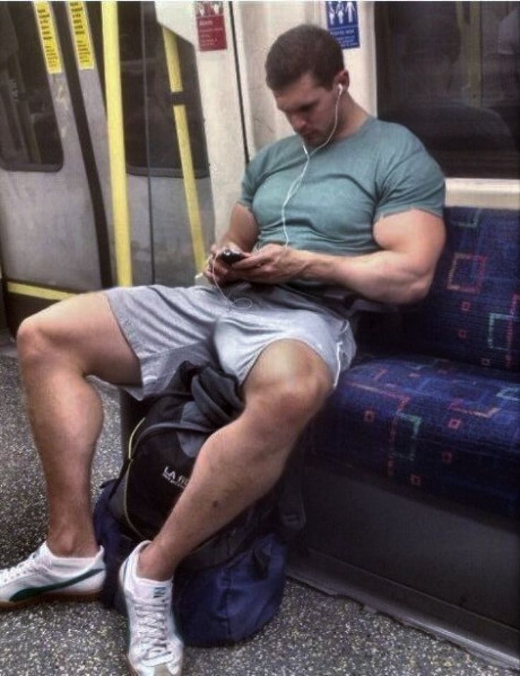 a man sitting on a subway train looking at his cell phone while listening to headphones