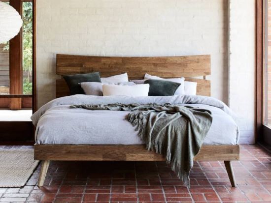 a bed with pillows and blankets in a room next to a brick flooring wall