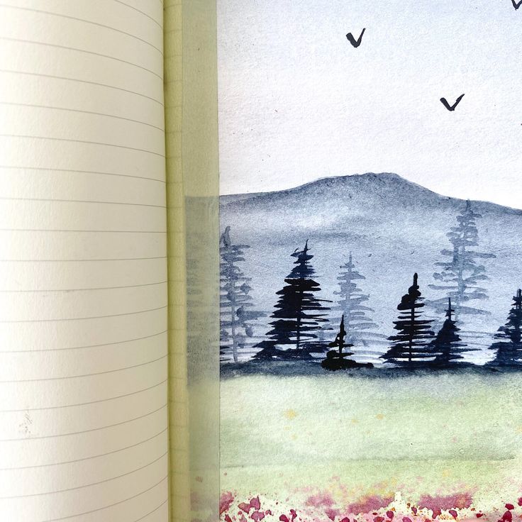 an open notebook with trees and birds flying over the mountains in watercolor on paper