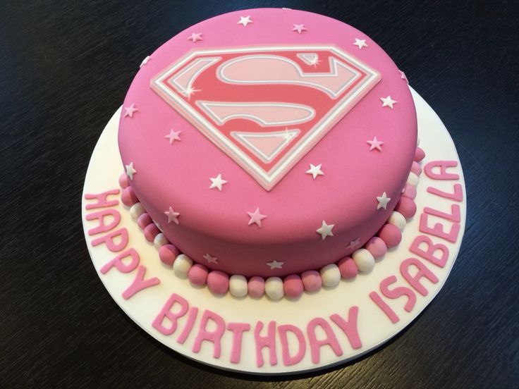 a pink birthday cake with a superman logo on it