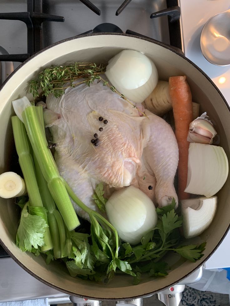 a pot filled with chicken, onions and celery on top of a stove