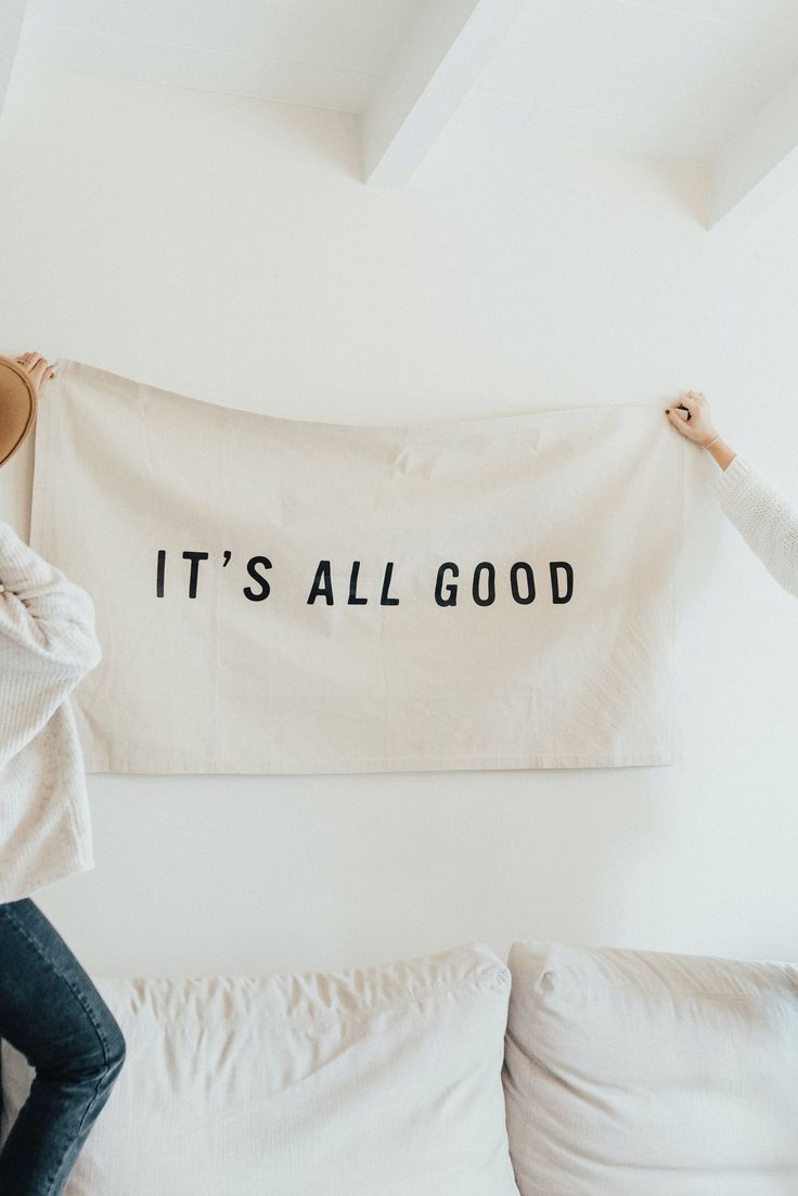 two women hanging up a banner that says it's all good on the wall