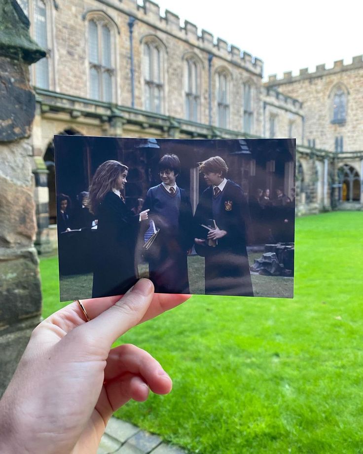 someone holding up a polaroid with harry potter in front of an old castle building