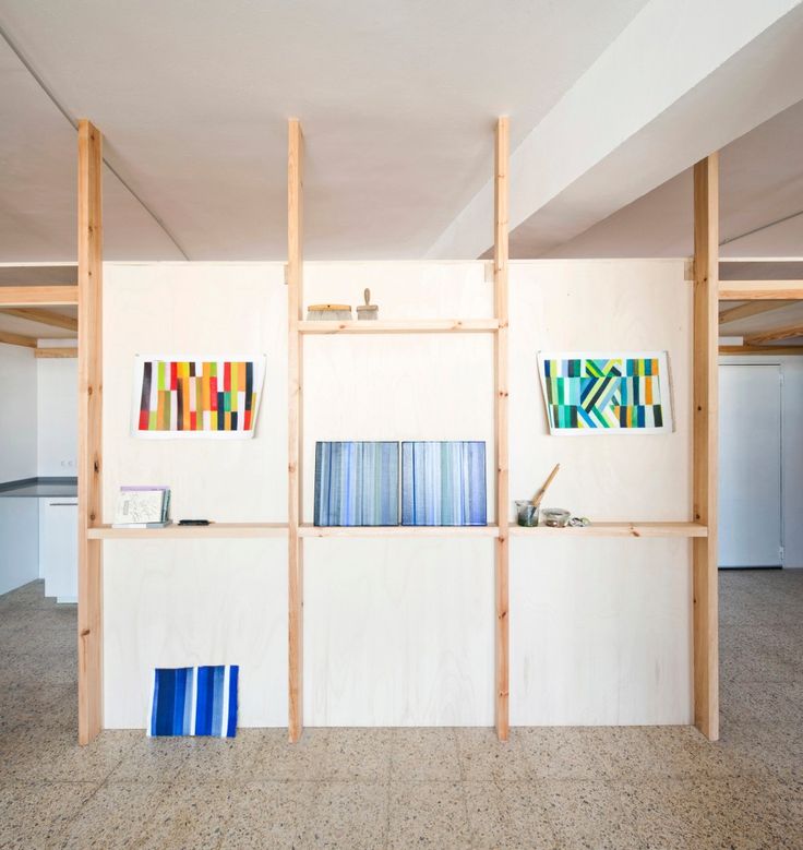 an empty room with shelves and paintings on the wall