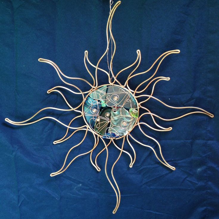 a metal sun sculpture on a blue background