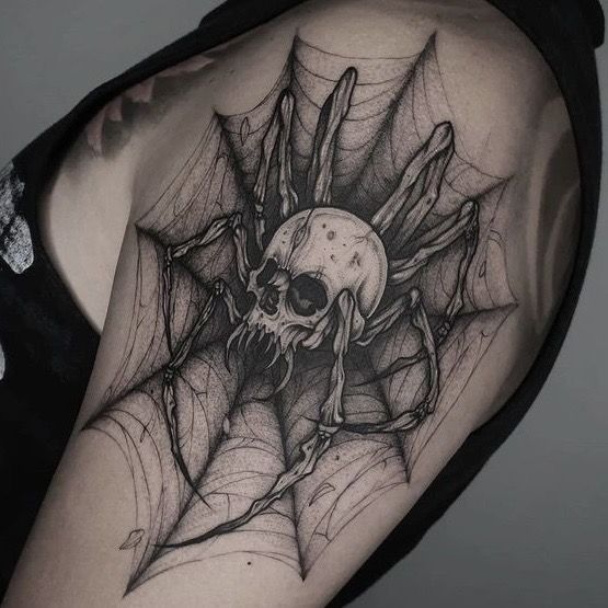 a woman's shoulder with a skull and spider web tattoo on her left arm