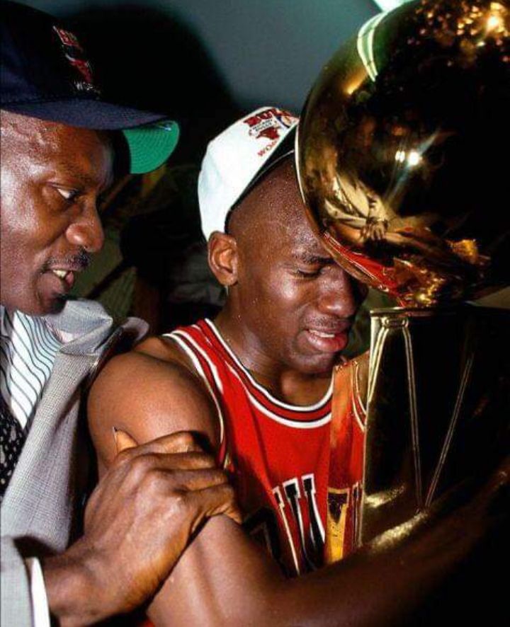 two men standing next to each other holding up a basketball in front of their face