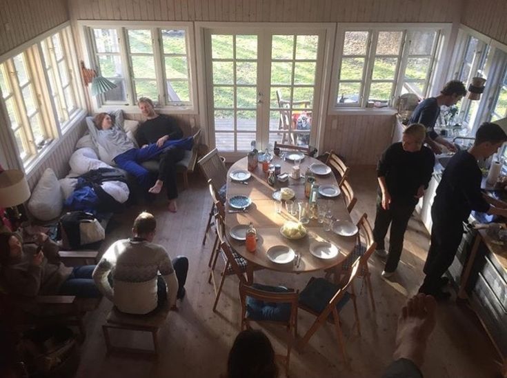 a group of people sitting around a table in a room with lots of windows and furniture