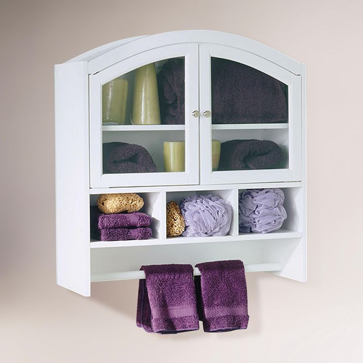 a white cabinet with purple towels hanging from it's sides and two candles on top