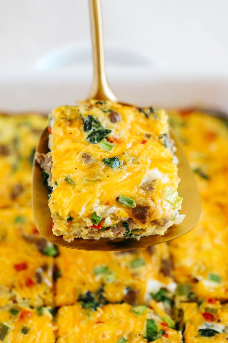 a spoon full of food that is being lifted from a casserole dish with broccoli, cheese and other toppings