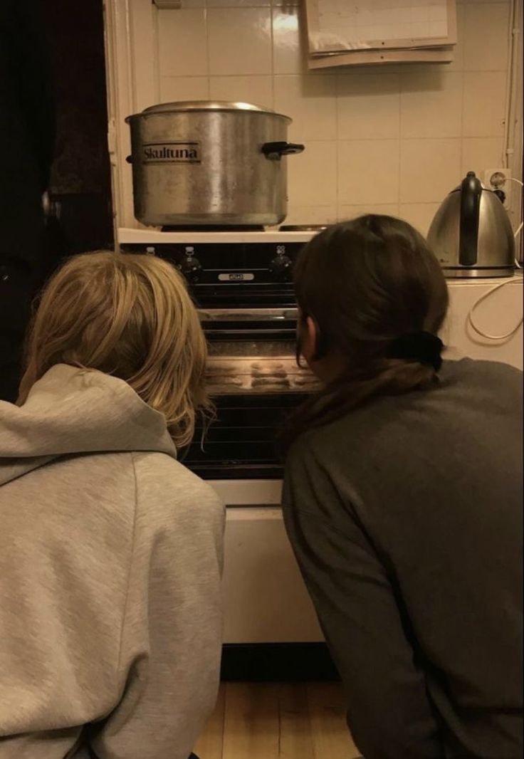 two people are looking into an oven in the kitchen