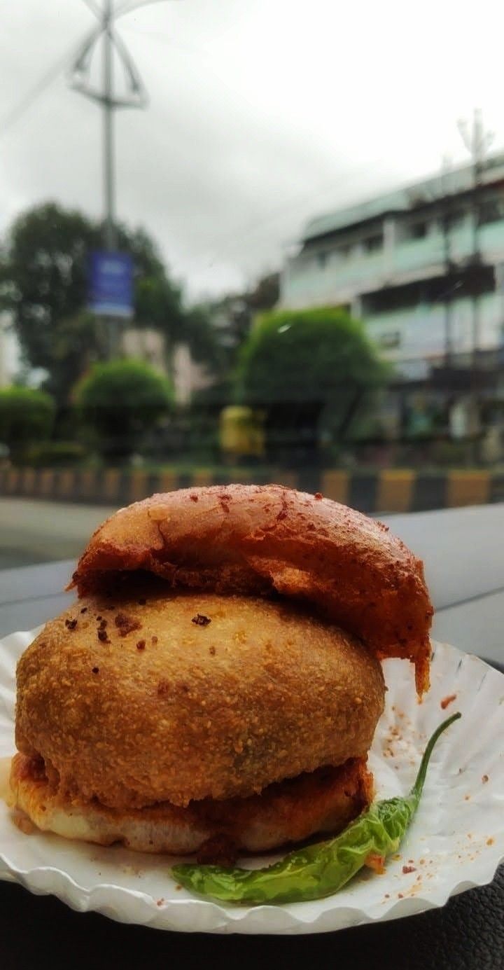 a fried chicken sandwich sitting on top of a paper plate in front of a building