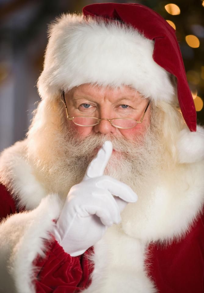 a man dressed as santa claus holding his finger up to his mouth