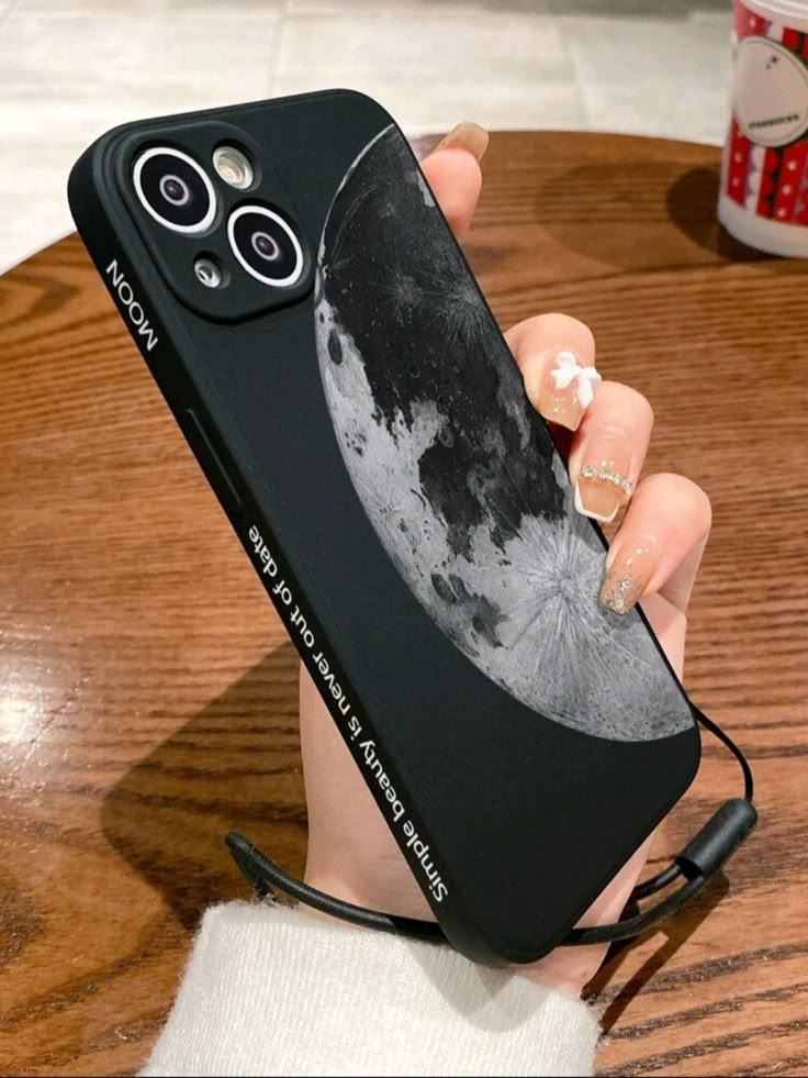 a woman's hand holding a cell phone case with an image of the moon on it