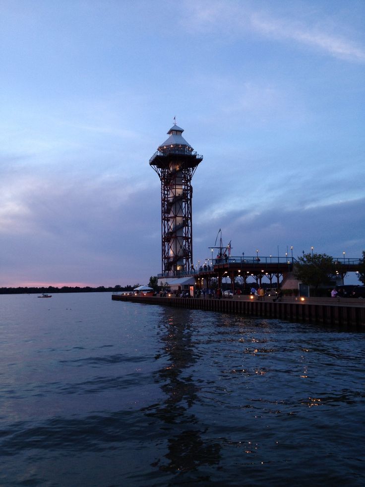 a large tower sitting on top of a body of water next to a pier at dusk