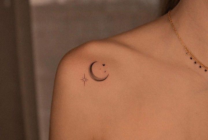 a woman with a small crescent tattoo on her left shoulder and the moon behind it