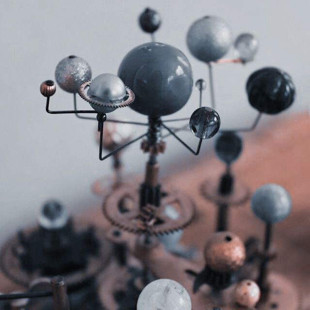 an assortment of metal and glass balls on top of a wooden table next to a clock