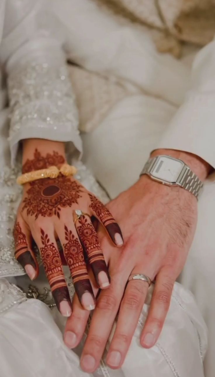 a man and woman holding hands with henna on them